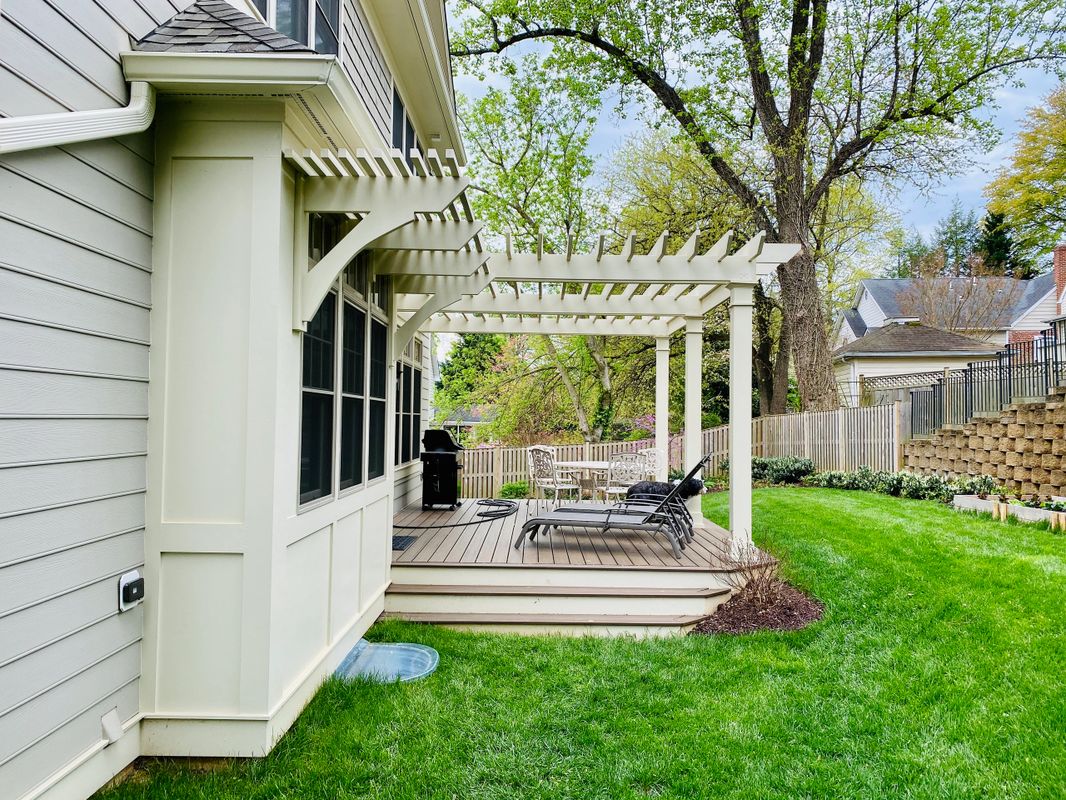 A white pergola sitting on top of a green lawn.