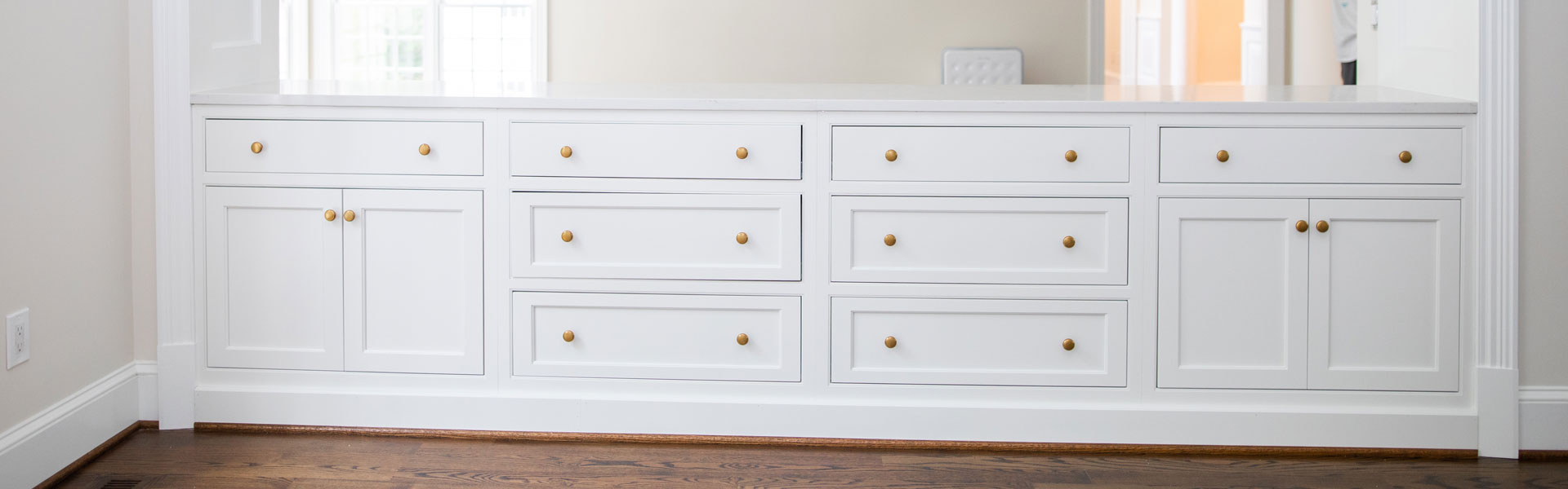 A white dresser with gold knobs and pulls.