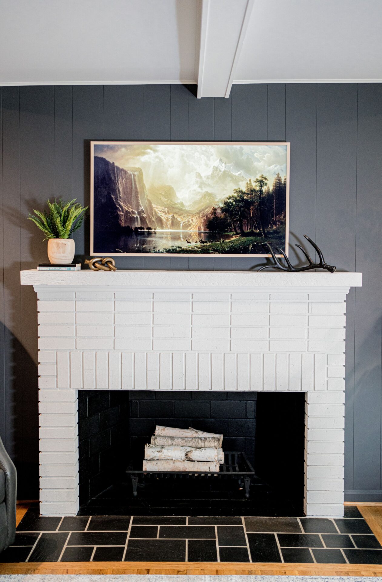 A television is mounted on the mantle of a fireplace.