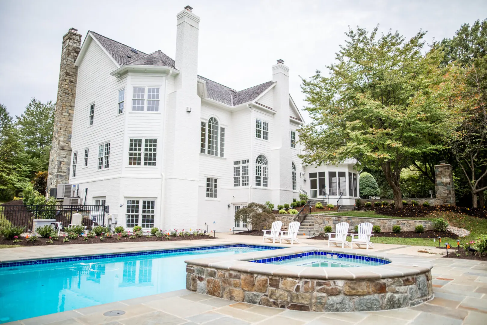 A large white house with a pool and hot tub.